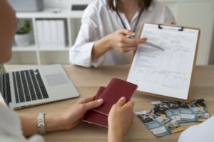 BMI Brokers insurance agent explaining health policy for Non-Lucrative Visa with British passports on desk.