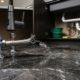 Tubería de agua rota inundando el suelo de mármol de un apartamento en Mijas.