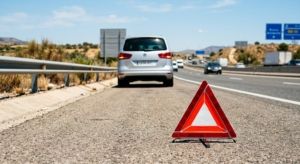 Triángulo de emergencia detrás de un coche familiar averiado en España.