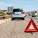 Triángulo de emergencia detrás de un coche familiar averiado en España.