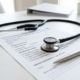 Medical stethoscope and health insurance application form on a desk.
