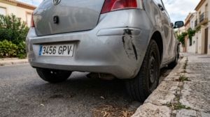 Scratched car bumper parked on a Spanish residential street.
